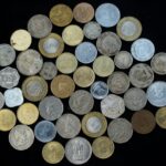 A variety of international coins displayed on a black background, showcasing different currencies and designs.